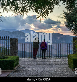 Un jeune couple s'établit à une clôture à la recherche sur le paysage au coucher du soleil ; de Ronda Ronda, province de Malaga, Espagne Banque D'Images