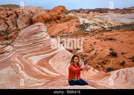 Woman taking photo selfies le feu vague rock formation de grès dans la Vallée de Feu State Park, Nevada. Banque D'Images