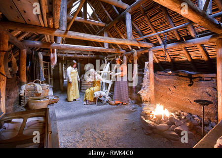 Parcs Canada les interprètes en costumes d'effectuer des tâches traditionnelles à l'intérieur d'une maison longue Viking recréé à L'Anse aux Meadows National Historic Site, L'Anse aux Meadows, Terre-Neuve, Canada Banque D'Images