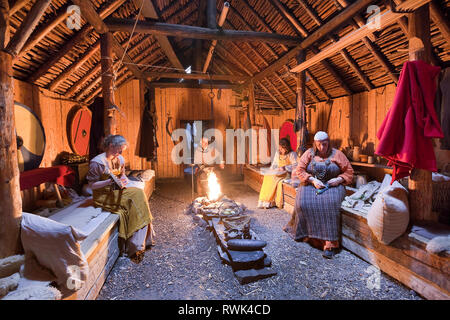 Parcs Canada les interprètes en costumes d'effectuer des tâches traditionnelles à l'intérieur d'une maison longue Viking recréé à L'Anse aux Meadows National Historic Site, L'Anse aux Meadows, Terre-Neuve, Canada Banque D'Images