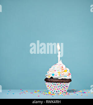 Birthday cupcake sprinkles et avec une bougie sur un fond bleu. Banque D'Images