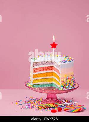 Gâteau d'anniversaire en couches colorées avec nutrifer et candy sur un fond rose. Banque D'Images