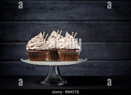 Trois petits gâteaux au chocolat avec glaçage buttercream sur un cake stand Banque D'Images