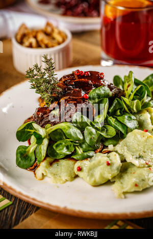 Joues de porc braisé en sauce au vin rouge brun avec gnocchi et bébés épinards sur un design classique plaque blanche Banque D'Images