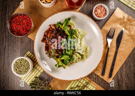 Joues de boeuf braisées au jus de viande avec gnocchi et bébés épinards Banque D'Images