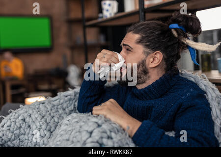 Triste agréable jeune homme tenant son nez Banque D'Images