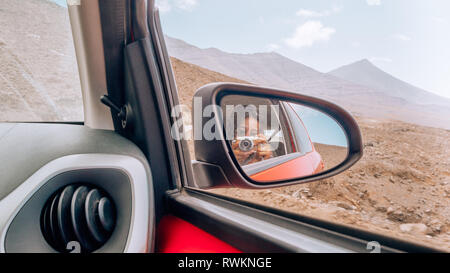 Woman taking a photo reflétée dans le miroir d'une voiture sur une route travel Banque D'Images