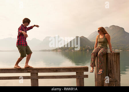 Jeune couple couchait sur la jetée, le lac d'Annecy, Annecy, Rhône-Alpes, France Banque D'Images