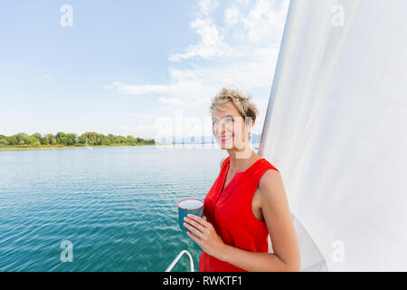 Young woman having coffee en navigation sur le lac de Chiemsee, en Bavière, Allemagne Banque D'Images