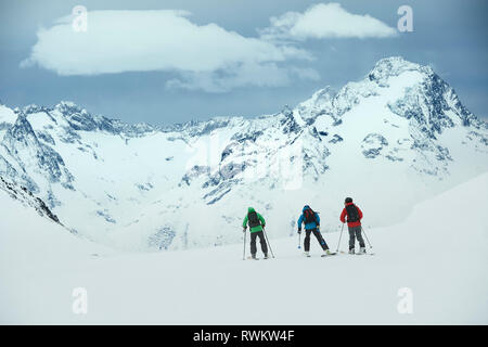 Paysage avec trois skieurs masculins vers ski montagne, vue arrière, Alpe-d'Huez, Rhône-Alpes, France Banque D'Images