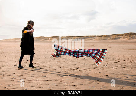 Femme chasing Beach Blanket Banque D'Images