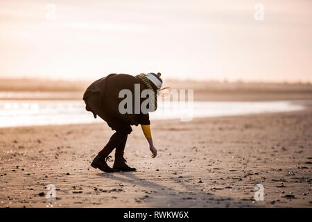 Femme la collecte des galets sur la plage Banque D'Images