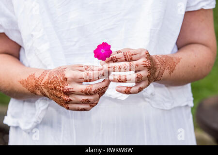 Femme en robe blanche avec tatouage au henné sur les mains holding flower Banque D'Images