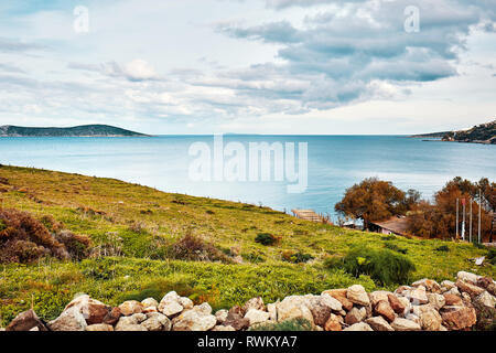 Vue de la baie d'cukurbuk Moody dans Gumuslık Bodrum, Mugla, Turquie sur une journée d'hiver. Belle mer tranquille, prairie et ciel paysage. Banque D'Images