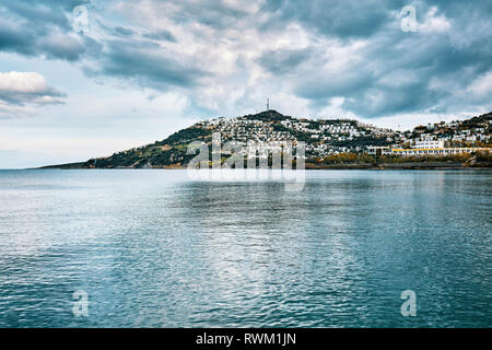 Vue de la baie d'Cukurbuk Moody à Bodrum, Mugla, Turquie, Gumusluk. La mer, la plage, la montagne et les colonies sur un ciel nuageux et spectaculaire d'hiver mélancolique da Banque D'Images