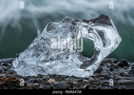 Morceau de glace sur la plage du Diamant, près de Jokusarlon, avec l'océan derrière elle le long de la côte sud de l'Islande, Islande Banque D'Images