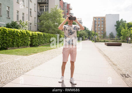L'homme à l'aide de lunettes de réalité virtuelle en milieu urbain de Berlin, Allemagne Banque D'Images
