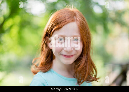 Red haired girl in garden portrait de la tête et des épaules, Banque D'Images