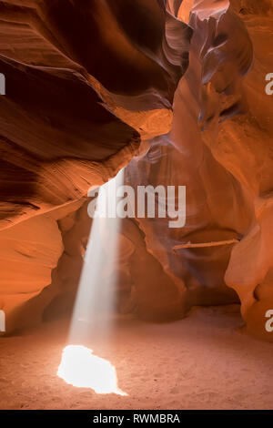 La lumière du soleil à travers un trou d'eau naturel dans le grès pour le sable ci-dessous, la région de Antelope Canyon, Arizona, États-Unis d'Amérique Banque D'Images