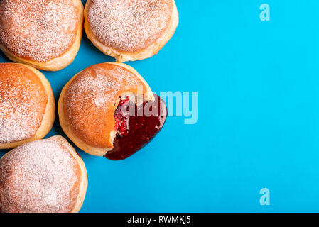 Bande de confiture beignets, rempli de gelée de fraises, couvert de sucre en poudre, sur un fond de papier bleu. Mise à plat avec un aliment sucré. Banque D'Images