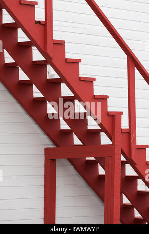 Image abstraite de l'escalier en bois rouge contre un mur blanc Banque D'Images