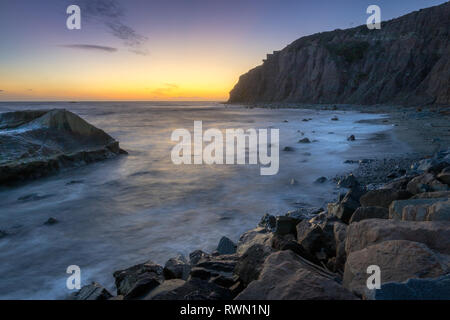 Une longue exposition photo de substitution, de hautes falaises et les vagues s'écraser dans un grand rock formation après le coucher du soleil, Dana Point, Californie Banque D'Images