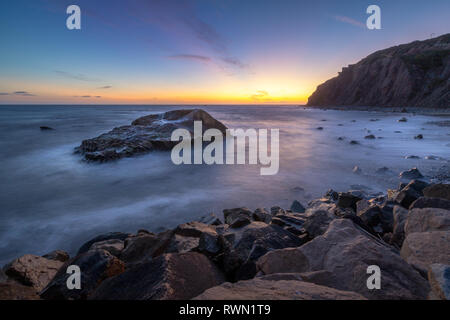 Une longue exposition photo de substitution, de hautes falaises et les vagues s'écraser dans un grand rock formation après le coucher du soleil, Dana Point, Californie Banque D'Images