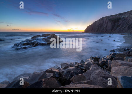 Une longue exposition photo de substitution, de hautes falaises et les vagues s'écraser dans un grand rock formation après le coucher du soleil, Dana Point, Californie Banque D'Images