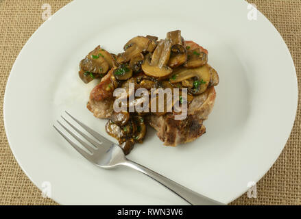 Côte de porc sauce aux champignons sur plaque blanche avec une fourchette Banque D'Images