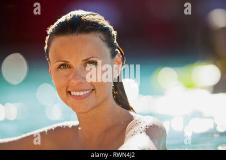 Portrait of a smiling young woman relaxing in a swimming pool. Banque D'Images