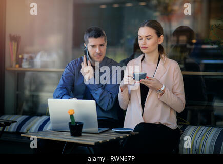 Deux entrepreneurs travaillant ensemble dans un café local. Young ensemble sur une terrasse de café. Attractive businesswoman drinking coffee Banque D'Images
