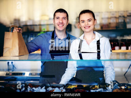Jeune homme et femme debout derrière le comptoir d'un restaurant. Derrière la cuisine Banque D'Images