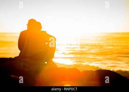 Coucher de soleil sur Hokitika beach avec deux jeunes touristes ejoying le coucher du soleil. Banque D'Images