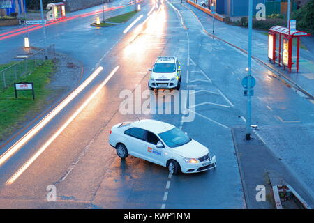 Location privée d'un véhicule se trouve sur une route à deux voies à Leeds, gardé par une voiture de police, après avoir heurté un crash barrière. Banque D'Images