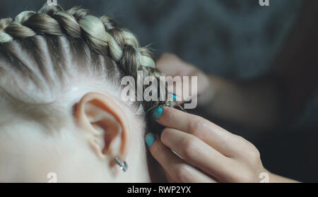 Le processus de tressage sur la fille tresses boxer's Head, le maître fait ses cheveux dans un salon de beauté, mains close-up Banque D'Images