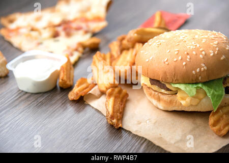 Le fast food. Hamburger, frites deluxe, pizza, fromage, laitue et sauce à la crème aigre. Banque D'Images