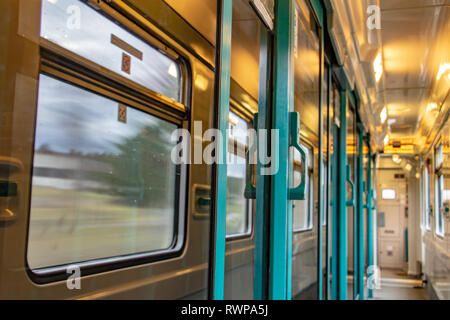 Le couloir du wagon avec un cadre de réflexion dans la vitre de la porte. L'intérieur du train en marche avec long corridor et des portes et fenêtres. Banque D'Images