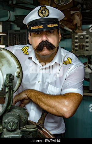 Un marin - ancien officier du sel dans l'uniforme, c'est la gouverne du navire avec un gouvernail. Le capitaine debout dans la timonerie du navire et à la recherche d'appareil photo. Banque D'Images