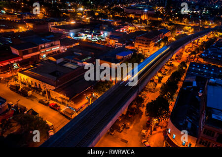 Une rame de métro, en passant au-dessus de Barrio Triste, une mécanique automobile, est vu d'un toit pendant la nuit à Medellín, Colombie. Banque D'Images