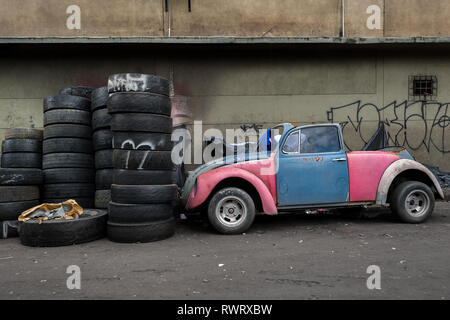 Une coccinelle Volkswagen épave de voiture, garée à côté d'une pile de pneus, est vu dans la rue de Barrio Triste à Medellín, Colombie. Banque D'Images