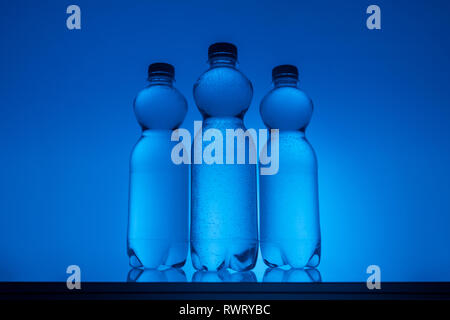 Image aux couleurs de bouteilles en plastique avec de l'eau sur fond bleu néon Banque D'Images