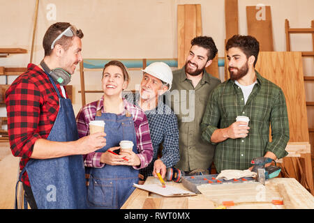 L'équipe d'artisans et apprentis ayant une pause café dans l'atelier de menuiserie Banque D'Images