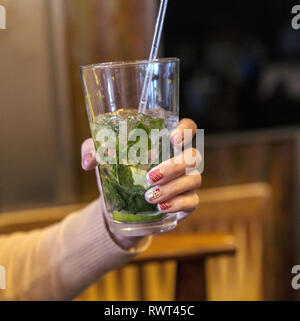 Jeune femme part avec Christmas manicure holding mojito cocktail Banque D'Images