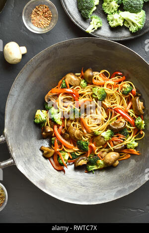 Close up d'udon nouilles sautés avec légumes en wok casserole sur fond noir en noir. Des légumes sautées avec les nouilles dans un style asiatique. Vue de dessus, f Banque D'Images