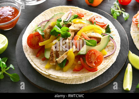 Close up of healthy tacos de poulet grillé viande et légumes sur table en pierre sombre Banque D'Images