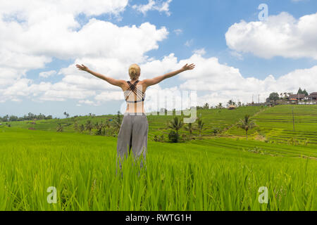 Ambiance détendue et informelle femme sportive, bras levé vers le ciel, appréciant nature pure de magnifiques rizières de Bali. Banque D'Images