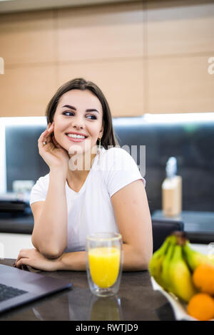 Vertical image d'une jeune femme assise devant son ordinateur dans la cuisine Banque D'Images