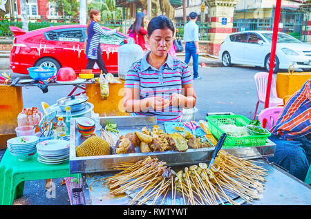 YANGON, MYANMAR - février 15, 2018 : le vendeur de la street food La cuisine les abats de porc sur les brochettes, le 15 février dans la région de Yangon. Banque D'Images