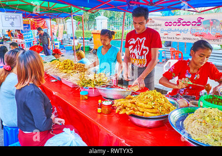 YANGON, MYANMAR - 15 février 2018 : Des vendeurs de la foire de l'alimentation de rue à la table, plein de plats locaux, tels que les nouilles avec les légumes, abats Banque D'Images