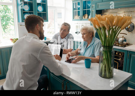 Advisor aide ses clients d'un aîné, donnant une consultation dans leur salle à manger. Planification de la retraite ou la gestion financière. Banque D'Images